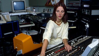 Elizabeth Parker is surrounded by a bank of circular desks, computer monitors and musical and computer keyboards. She's at the controls.