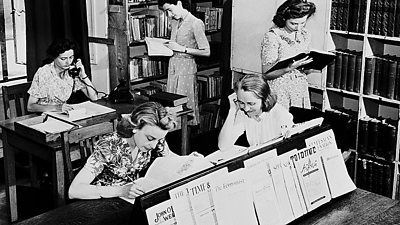 A slightly staged photo inside a library - one woman is on a telephone, the others study books studiously. 