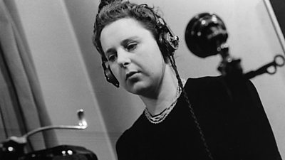 A strikingly angled image of a woman wearing headphones transcribing a telephone call on her typewriter.