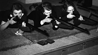 Three women aiming rifles at a rifle range. 