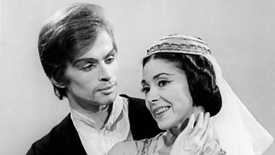 A man and a woman, heavily made up, the woman in a headdress. Margot Fonteyn is on the right.