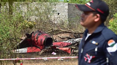 An Indian Air Force personnel walks past the wreckage of an aircraft