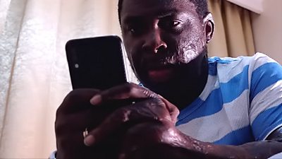 Obumneke-Okeke Kosisochukwu, with facial scars, looks at his phone