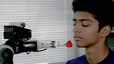 A man being fed a strawberry by the University of Washington's ADA robot