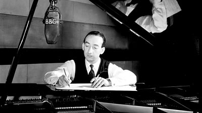 Stanley Black writes a score at a grand piano