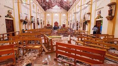 Crime scene officials inspect the site of a bomb blast inside a church in Negombo