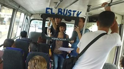 Woman holds a cardboard box reading El Bus TV