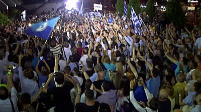 A crowd waves flags and phones in the air