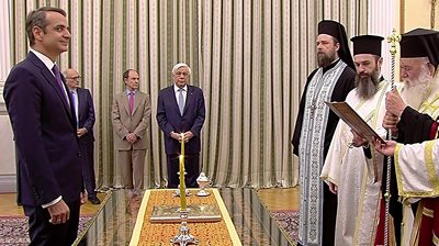 Kyriakos Mitsotakis stands in front of a group of Greek Orthodox priests