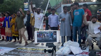 People standing on a street are filmed by a mobile phone on a tripod