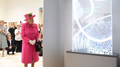 The Queen looks at a plaque