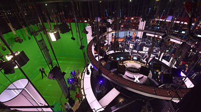 An overhead shot of the whole election studio, the green screen area is now huge. The presenters are arranged in a circular set. 