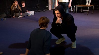 An actor crouching in front of another