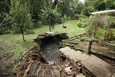 A sink hole in a garden after heavy rain.