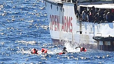 Migrants in water next to Open Arms rescue ship