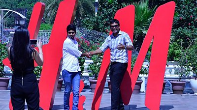 Indians pose in front of the H&M logo when the store launched in India.