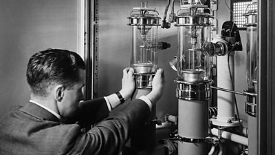 An engineer fixes a large valve into radio apparatus.