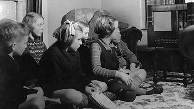 Children gather around a radio set