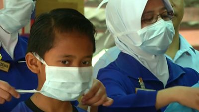 Children are shown how to wear face masks