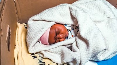 A newborn baby in a care box