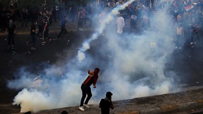Demonstrator throws a tear gas canister in Baghdad