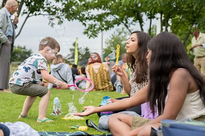 Charity photo for Family Action, a group of people blowing bubbles whilst sat on a grass and having a picnic