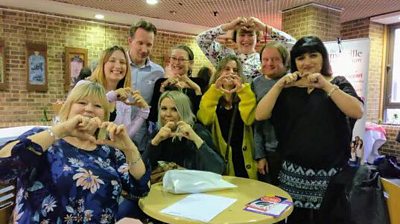 Picture of a group of people signing hearts with their hands from  Hearts and Minds - Supporting peer-to-peer meet-ups for those with ACHD