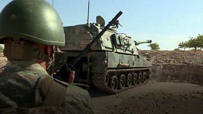 A Turkish soldier stands next to a tank