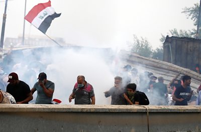 Demonstrators cover their faces from tear gas during a protest in Baghdad on 25 October 2019