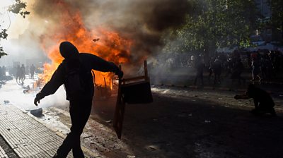 protester by a fire in Chile`