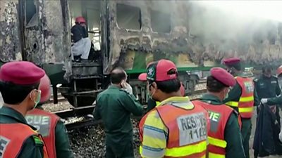 Emergency authorities survey the wreckage of a train fire in Pakistan