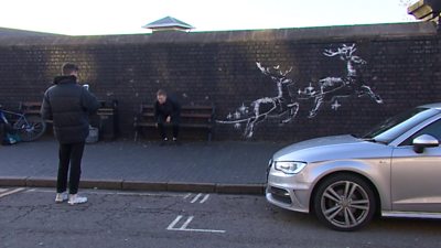 Resident in front of Banksy artwork