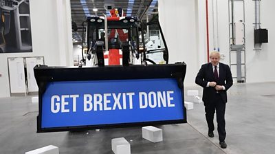 Boris Johnson stands next to digger