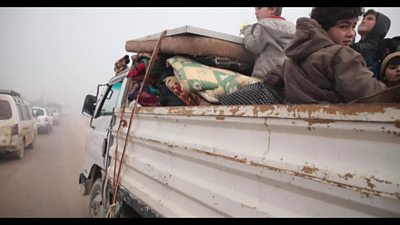 Family travel in a truck heading north away from air strikes in Idlib province, Syria