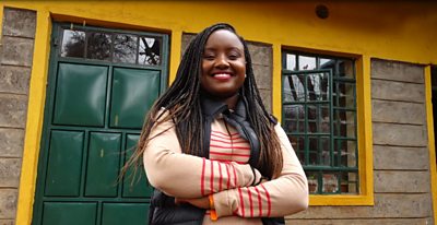 Waira Njiru smiles in front of a school building