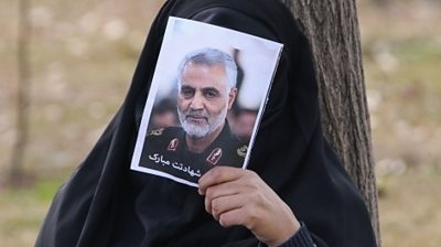 woman covers face with photo of Soleimani, Tehran