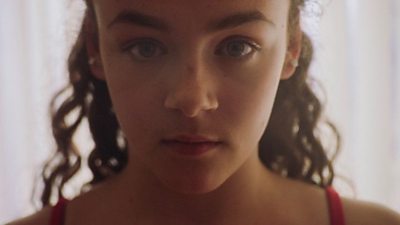 A young gymnast stares straight into the camera.