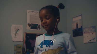 A little girl in a room wearing headphones