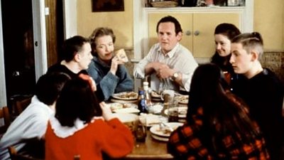 A man sits at the head of the table of his large family