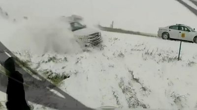 A man seems oblivious as truck careens off a motorway and plummets towards him down a snowy verge.