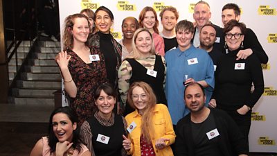 A group of writers of various genders smile at the camera