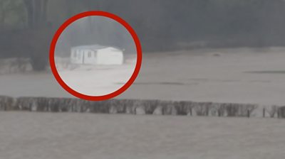 A caravan highlighted floating in flood water