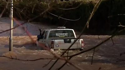 4 x 4 truck with 'recovery' markings in rear windscreen floats on flooded road