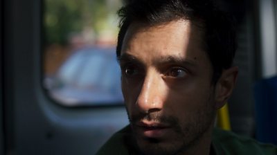 Riz Ahmed in a van looking tense. 