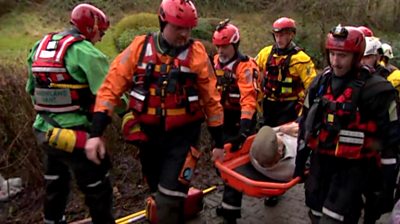Rescuers carry a man to safety in flood water