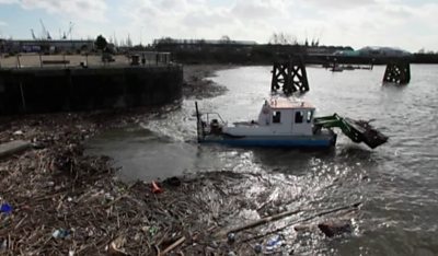 A boat cleaning debris out of the River Taff