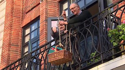 Suzi and David Ashcroft raising a basket to their balcony
