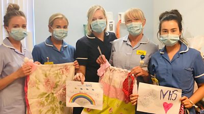 Midwife Vicki Hill (centre) with NHS staff holding the bags