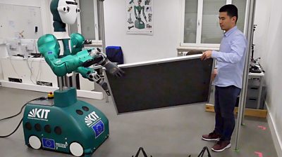 Robot helping a man lift a panel