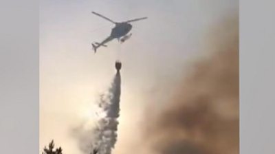 Footage shows a helicopter 'water bombing' the site of a forest fire which had flared up